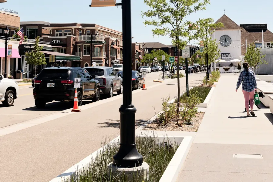 The Ensley 55+ Luxury Apartments with A streetlamp with an American flag and "Love Local" banner on a sunny downtown street with people walking.