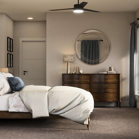 The Ensley 55+ Luxury Apartments with Modern bedroom with a neatly made bed, wooden furniture, and wall art; sunlight streams through the window.