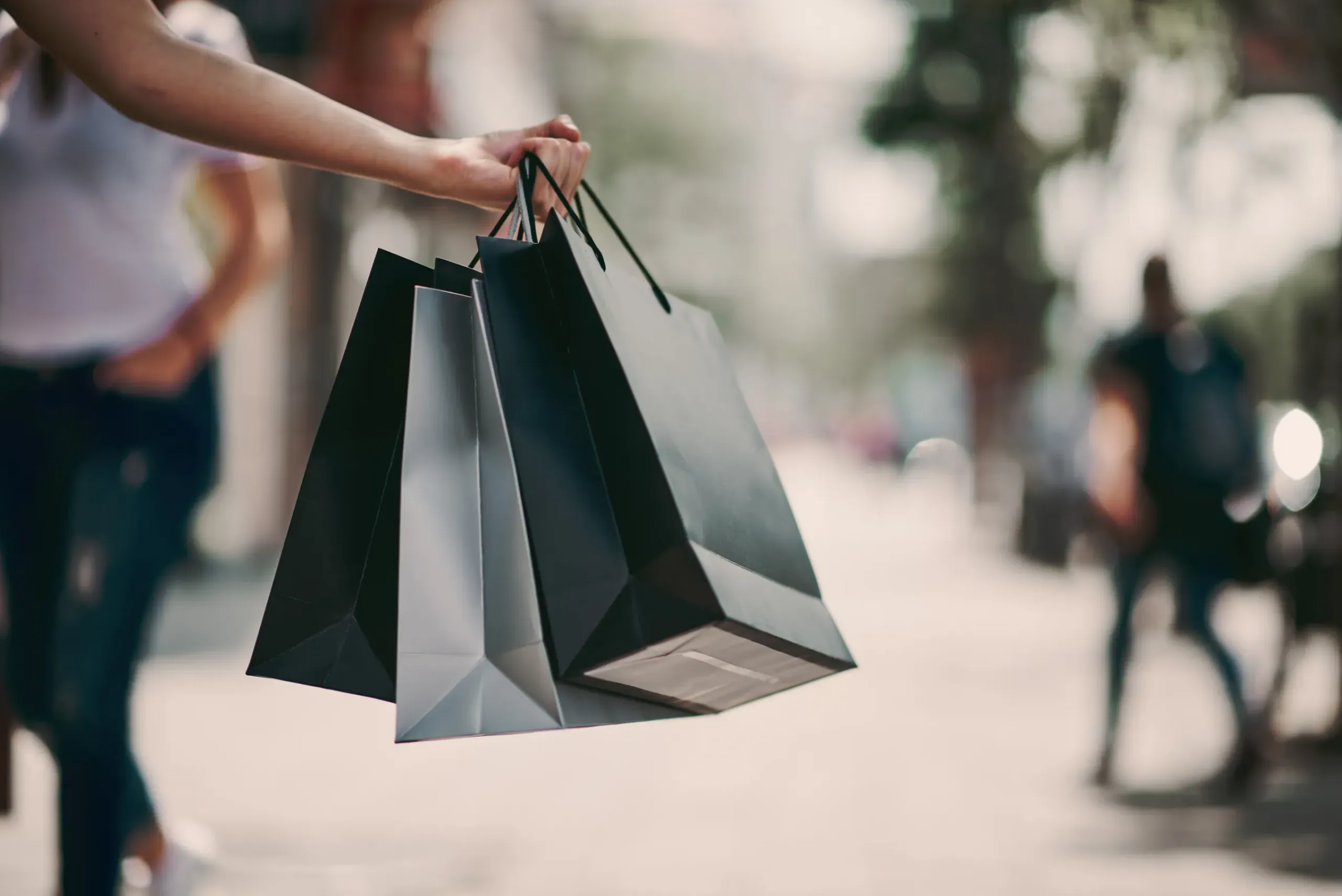 The Ensley 55+ Luxury Apartments with A person holding several shopping bags outdoors on a city street.